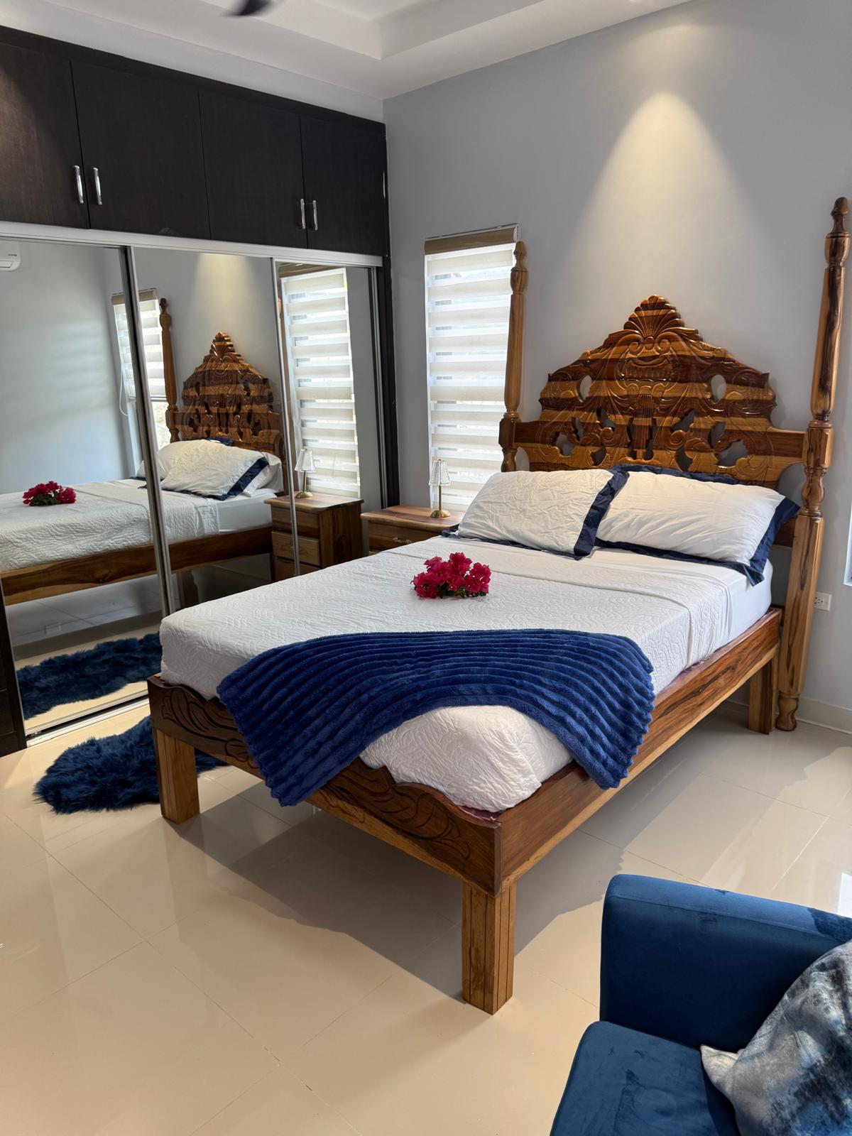 Bedroom with carved wood bed and blue throw